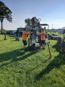 Two men assisting with moving headstone.